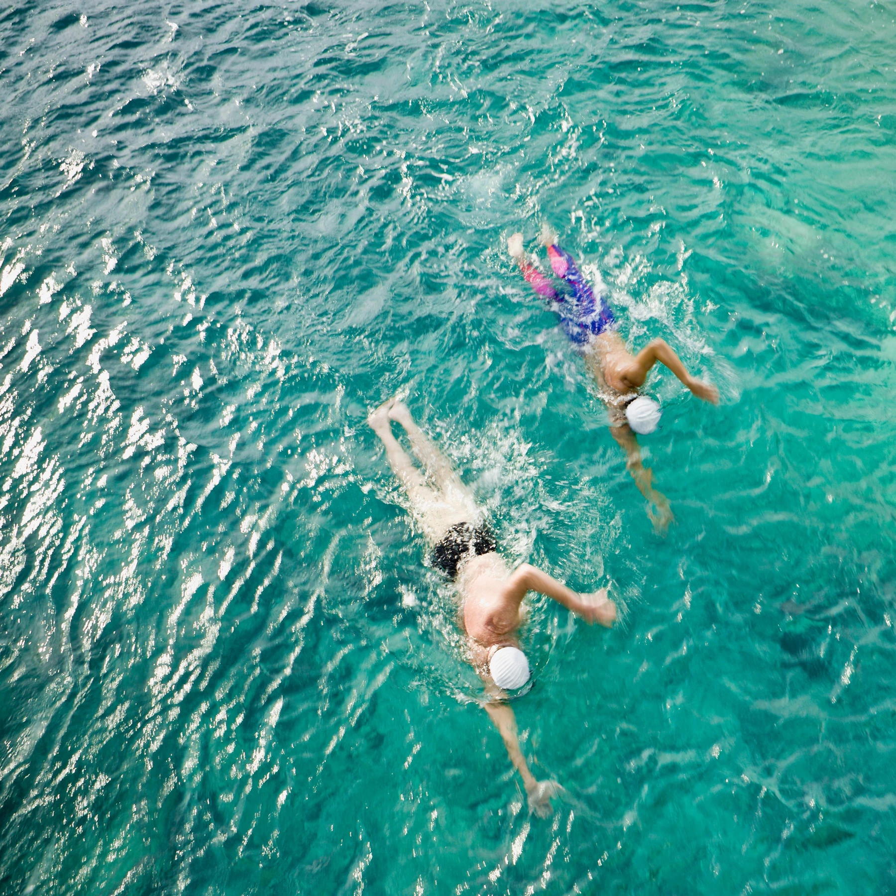 Swimmers in clear turquoise coastal water